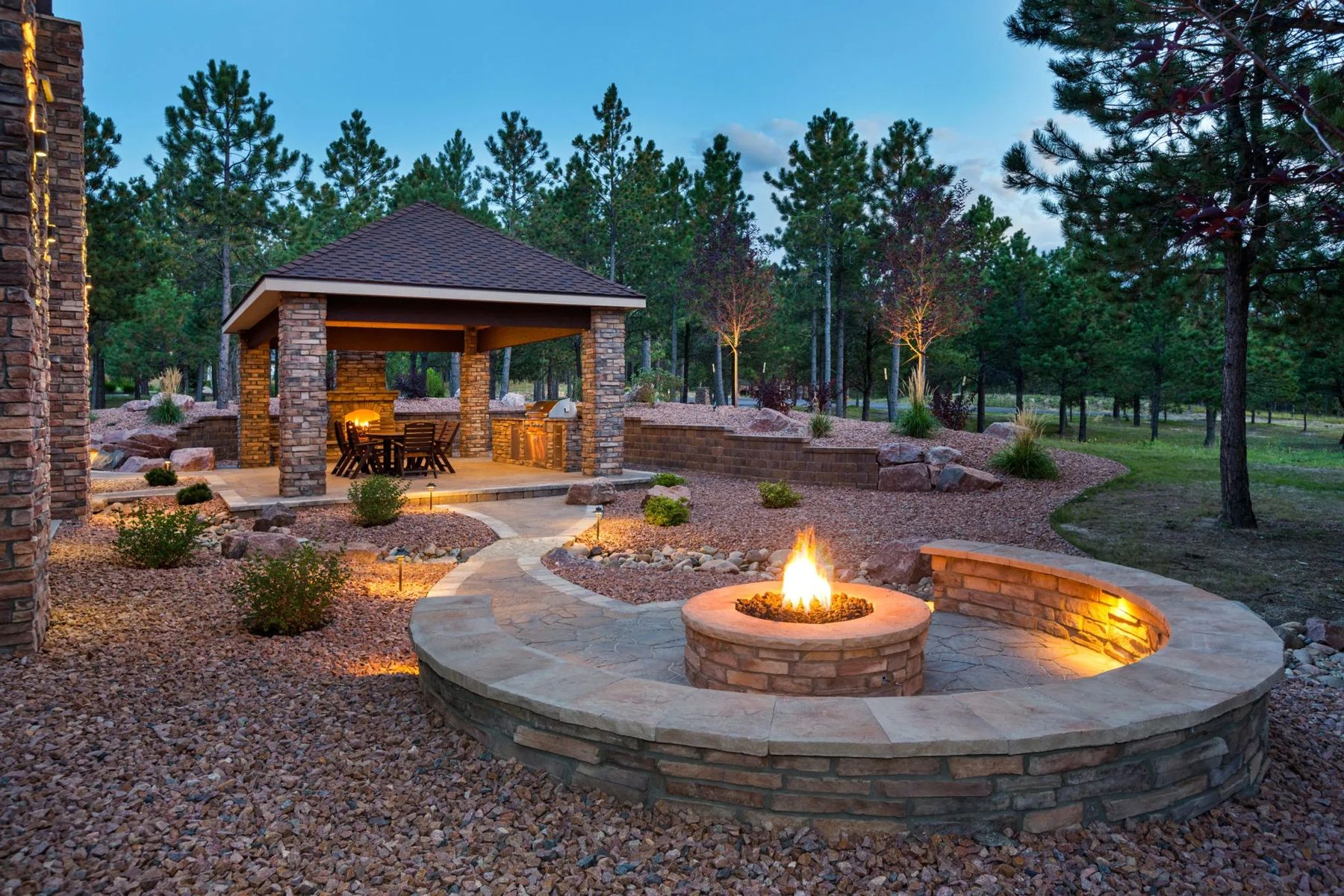 Stone fire pit and covered pavilion lit at dusk on a Park City estate